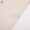 Close-up of elegant white pearl hair claw clip with minimalist design on neutral background - Semi-circle