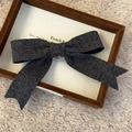 Detail showing high-quality knitted bow hair clip on a premium velvet display tray - Dark Gray