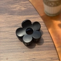Gros plan d'une pince à cheveux noire mate en forme de fleur sur une surface en bois - 5cm / Noir mat
