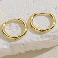 Makroaufnahme polierter goldener Creolen auf einem weißen, strukturierten Mineralstein - 15MM Glatte Creolen / Gold