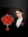 Elegant gold flower brooch with red crystals and teardrop pendant on black background - Red Dangle Flower