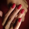 Glossy solid red press-on nails in medium square shape shown on hand display - True Red