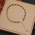 Elegant gold and black woven leather necklace with a T-toggle clasp and golden ball charm - Spherical