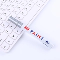 White oil-based paint marker with 2.8mm tip and silver cap on white keyboard background - Silver
