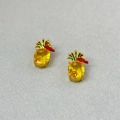 Close-up of yellow pineapple stud earrings with faceted crystals and green leaf accents - Yellow