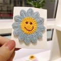 Handmade knitted blue daisy hair clip with a yellow smiley face embroidery detail - Grey Blue Smiley Flower