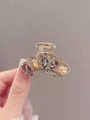 Golden flower hair claw with purple and yellow crystals held in hand for detail - Rhinestone Crown Claw