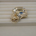 Macro shot of abstract gold face brooch with blue eyes and crystal inlay on jewelry tray - Classic / Gold