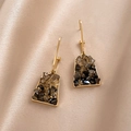 Detailed close-up of golden trapezoid earrings with brown crystals on beige silk fabric - Silver Needle - Black Geometric Earrings