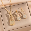 Golden safety pin necklace and earrings set with micro-pave cubic zirconia on beige box - Gold Safety Pin Jewelry Set (835)