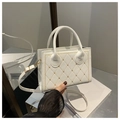 Detail of white quilted PU leather handbag with gold metal clasp and cross stitching - White