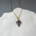 Macro shot of gold cross pendant with deep blue square zircons and white diamond halo - Blue Zircon Cross