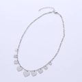 Collana minimalista in argento con ciondoli a cuore e catena Figaro su sfondo bianco - Color Acciaio