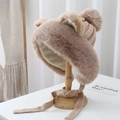 Detail of khaki plush winter hat with cute bear ears and fuzzy pompom on a wooden stand - Khaki