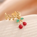 Detalle de anillo de vid dorado con colgantes de cerezas rojas y verdes en soporte - Anillo de Colgante de Cereza(J-2004)