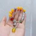 Ethnic agate bead bracelet with silver fish and lotus bell charms on a hand display - Yellow Slender Fish Bracelet