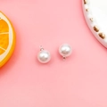 Detail von runden weißen Perlenanhängern mit Silberösen auf rosa Hintergrund - Silber Kappe Runde Perle 10mm