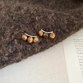 Macro view of vintage triple-bead flower earrings on a textured brown knit backdrop - Three-Bead Curved Row Style