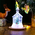 Close-up of glowing LED Christmas church lantern with snow effect on wooden base - Christmas Tree