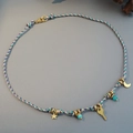 Handmade woven necklace with gold moon key pendants and turquoise beads on blue background - Purple Woven Star Moon Pendant