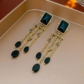 Detail of vintage long earrings with gold chains, black square gems, and oval beads - Gold