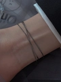 Primer plano de una pulsera cruzada negra de doble capa en una muñeca femenina - Color gunmetal