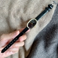 Detail view of oval black watch face with gold casing and black leather strap - Black Black Dial