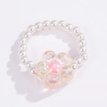 Dettaglio di un anello di perline bianche con un ciondolo a forma di fiore rosa cangiante - Fiore Rosa Iridescente