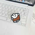 Close-up of a white embroidered cartoon bear pin placed on a white laptop keyboard - White Rabbit