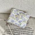 Macro view of blue floral quilted cotton makeup bag with zip closure and fabric label - Blue Flower