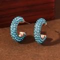 Macro shot of sky blue crystal studs and gold C-shaped alloy earrings on wood - Lake Blue With KC Gold