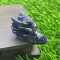 Deep blue natural stone dragon head carving on a dark wooden base with grass background - Blue Sodalite
