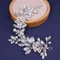 Detalle de diadema nupcial con cristales de hoja y perlas sobre fondo azulado - Plateado