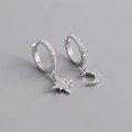 Macro shot of asymmetric s925 silver star and moon earrings with cubic zirconia stones - Silver