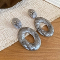 Detalle de pendientes de aro en acrílico marmolado con cruces de plata en lino - Gris