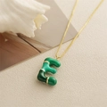 Dettaglio del ciondolo lettera E con smalto verde e texture bambù su catena dorata - Lettera E