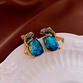 Elegant gold koi earrings with blue stones and colorful rhinestones on a white plate - Koi Fish / Blue