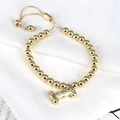 Detail of adjustable gold beaded bracelet with zircon-inlaid letter I charm and sphere ends - Letter I