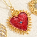 Macro detail of a red heart pendant with a blue eye stone and gold rose accent - Red Enamel Heart Necklace-Sacred Heart Evil Eye Style