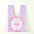 Close-up of a purple knitted tote bag with a white flower pattern and orange text - Purple Large Floral