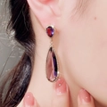 Nahaufnahme eines Vintage-Ohrrings mit lila Zirkon-Tropfen und Vergoldung am Modell getragen - Lila Wassertropfen / Lila