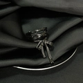 Detailed close-up of dark metal bow-shaped ring on black silk with zircon accents - Adjustable Open / Black Bow Style