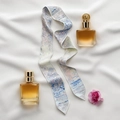 Blue and white silk scarf hairband shown in a flat lay with perfume and flower on white fabric - Snow Scene