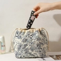 Detailed shot of beige quilted floral pouch being used for storing skincare cosmetics - Navy Floral