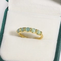 Elegant gold ring featuring six light green cat eye stones on a white velvet surface - Six Pale Green Cat's Eye Gemstones Row Inlay Style (金色25)
