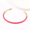 Detail of bohemian gold and rose red enamel spiral open bangle on white tray - Rose Gold