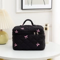 Close-up of black quilted makeup bag with pink bow embroidery and double zippers - Black