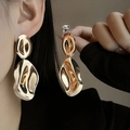 Close-up of golden irregular wavy drop earrings on model showing metallic luster - E4775 Wave Large Pendant / Gold