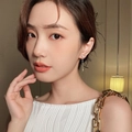 Close-up of heart-shaped diamond earrings with delicate gold chain tassels on model - Gold