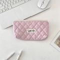 Detailed close-up of pink quilted makeup bag with rhombic stitching and white logo tag - Sakura Pink